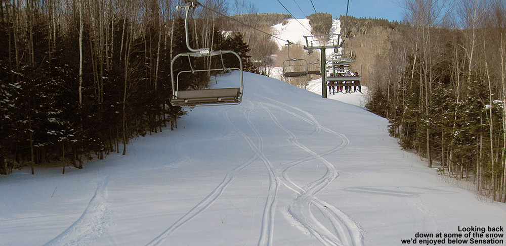 An image of ski tracks in the powder underneath the Sensation High Speed Quad Chairlift at Stowe Mountain Resort in Vermont