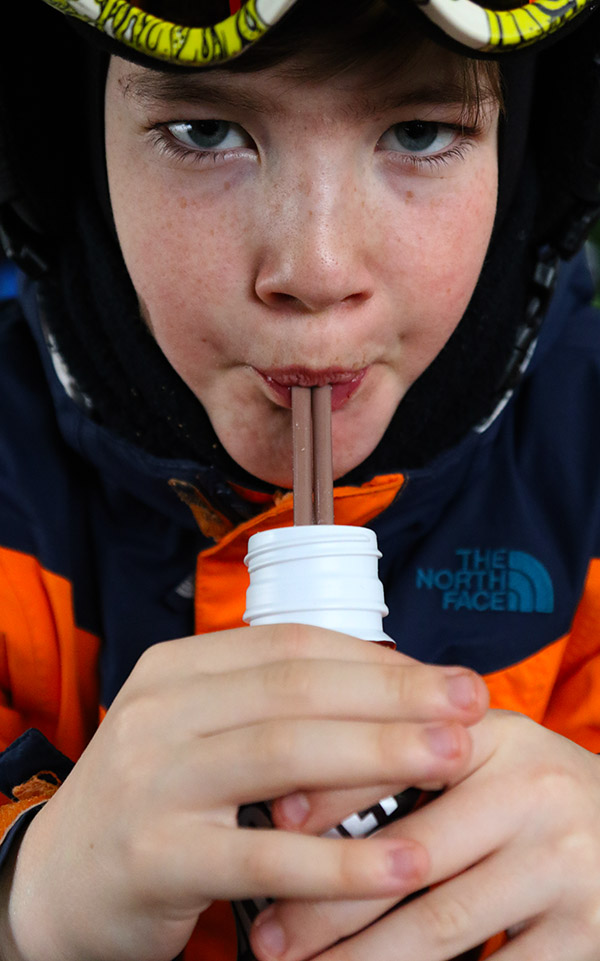 An image of Dylan drinking some chocolate milk with two straws in the base lodge at Bolton Valley Ski Resort in Vermont