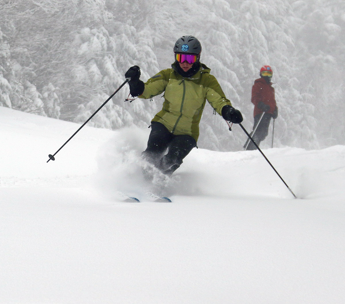 An image of Erica getting some powder turns and Dylan looking on from behind during Winter Storm Jacob at Bolton Valley Ski Resort in Vermont
