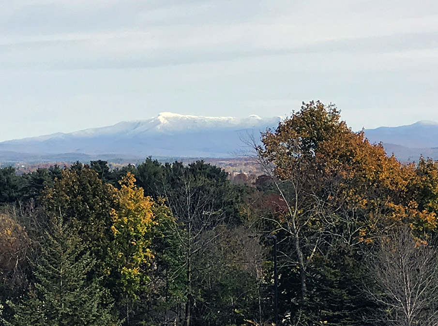 An image of Mt. Mansfield in Vermont taken from the Burlington area in late October showing some valley foliage and snow in the mountain peaks from a recent storm