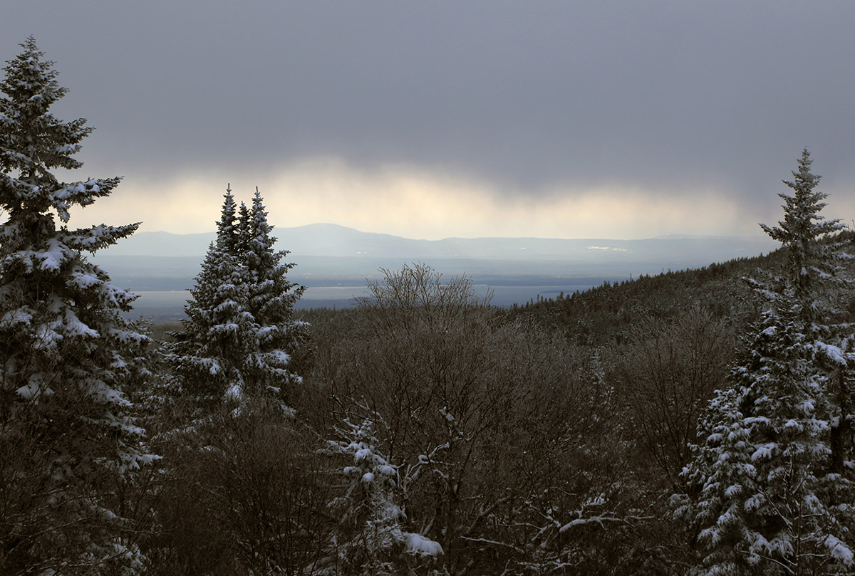 An image of low clouds and whisps of falling snow looking west toward the Champlain Valley during a late-April snowstorm at Bolton Valley Ski Resort in Vermont