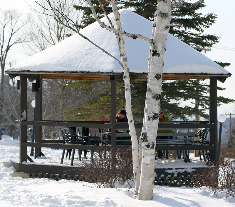 An image of a couple of people sitting in the Gazebo in the Village Circle at Bolton Valley Ski Resort in Vermont