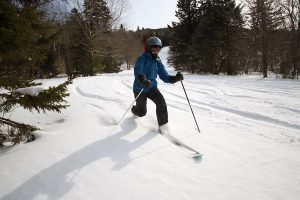 An image of Erica Telemark skiing in powder on the Cougar trail at Bolton Valley Ski Resort in Vermont