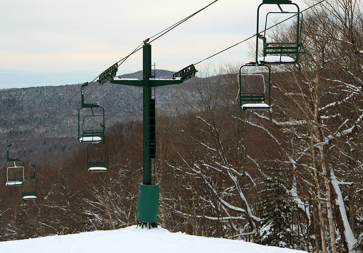 An image of the Wilderness Double Chairlift with snow on the chairs at Bolton Valley Ski Resort in Vermont