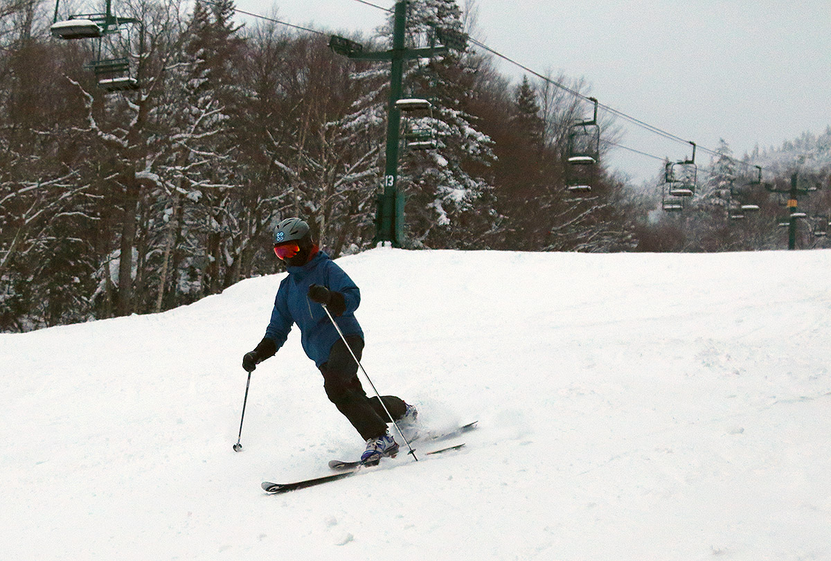 An image of Erica Telemark skiing in packed snow on the Wilderness Lift Line trail at Bolton Valley Resort in Vermont