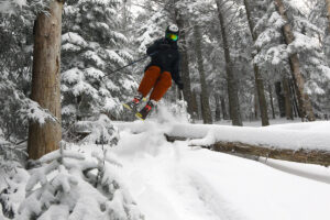 An image of Ty jumping over a log while tree skiing in the Snow Hole area at Bolton Valley Ski Resort in Vermont