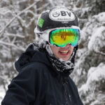 An image of Ty smiling after taking a tumble in the powder while Telemark skiing in the trees at Bolton Valley Resort in Vermont