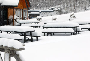 An image of snow accumulations from Winter Storm Sage on picnic tables and ski racks outside the Timberline Lodge at Bolton Valley Ski Resort in Vermont