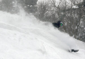 An image of Coline sending up a wall fo powder snow as he skis down the steep headwall of the Wilderness Liftline at Bolton Valley Resort in Vermont
