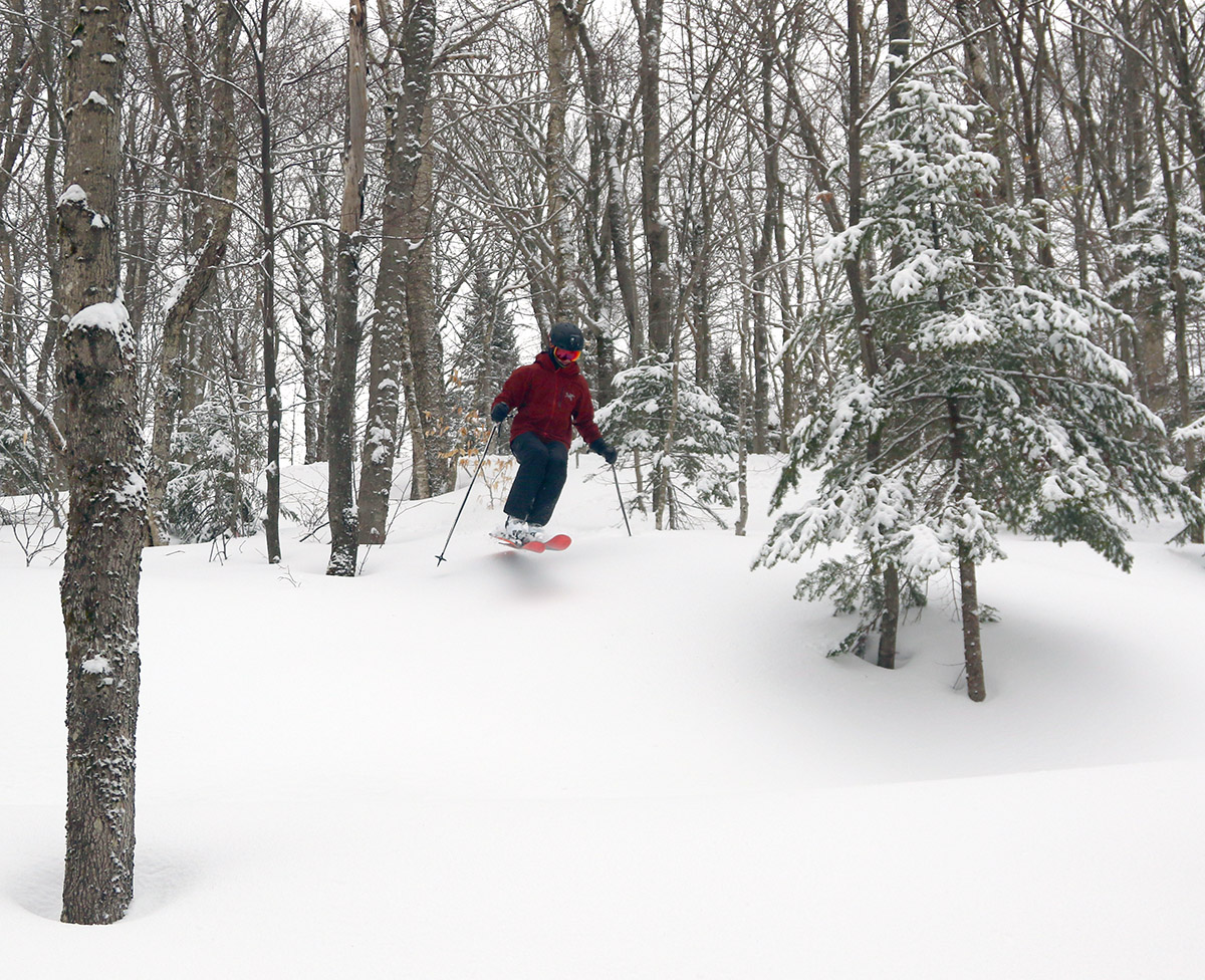 An image of Dylan jumping into some powder skiing in the trees of the Snowflake Lift after a late March snowstorm at Bolton Valley Ski Resort in Vermont