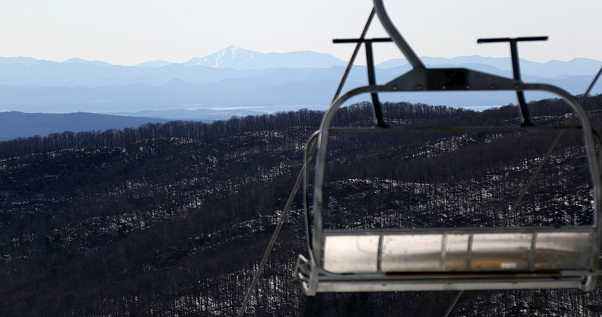 An image of Lake Champlain and the Adirondack Mountains of New York taken from the top of the Timberline Quad Chairlift at Bolton Valley Ski Resort in Vermont