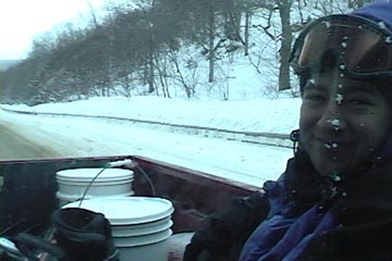 An image of Jay catching a ride in the back of Dave's pickup truck returning to the top of the pass on Route 242 while backcountry ski touring on Gilpin Mountain near Jay Peak Resort in Vermont
