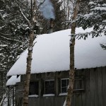 An image of the Bryant Cabin with smoke coming from the chimney on the Nordic/backcountry trail network at Bolton Valley Ski Resort in Vermont