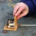 An image of a s'more being assembled at the fire pit in the center of the Spruce Peak Village at Stowe Mountain Ski Resort in Vermont