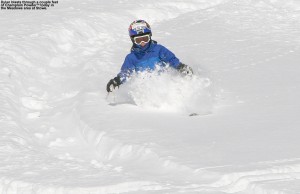 An image of Dylan skiing some deep powder in the sunshine above the Meadows Trail at Stowe Mountain Resort in Vermont
