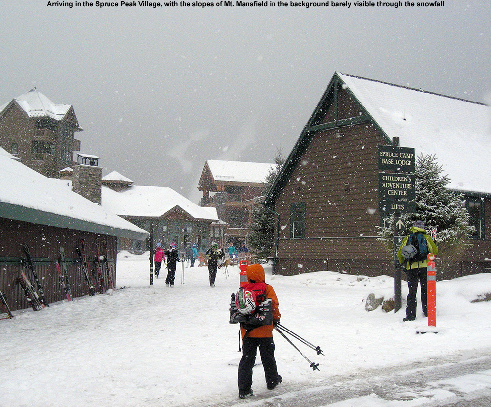 An image of arriving at the Spruce Peak Village at Stowe Ski Resort in Vermont with snow falling and a couple of trails on Mt. Mansfield just visible in the background 