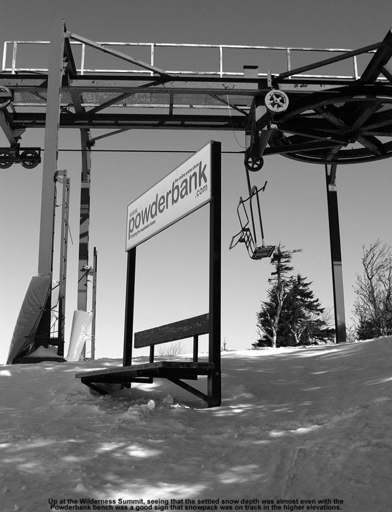 An image of the bench with the Powderbank sign at the summit of the Wilderness area at Bolton Valley Ski Resort in Vermont - the snowpack is several feet deep and is just about level with the seat of the bench.