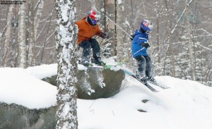 An image of Ty and Dylan jump off a rock into the powder in the Wilderness Woods at Bolton Valley Ski Resort in Vermont