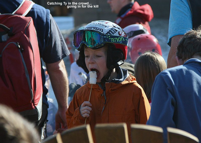 An image of Ty eating toasted marshmallows on a stick among the crowd at the Spruce Peak Village fire pit at Stowe Mountain Ski Resort in Vermont