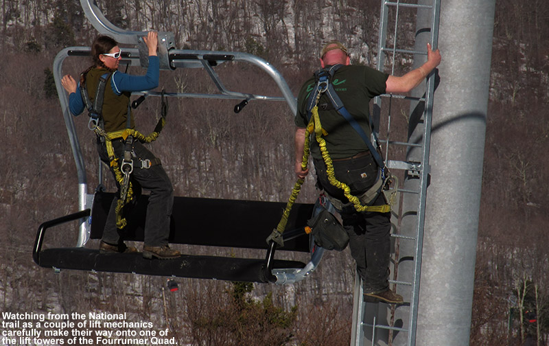 An image of two lift mechanics with safety harnesses moving from a chair on Stowe's Fourrunner Quad to one of the towers to perform maintenance.
