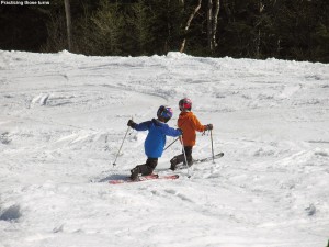 An image of Ty and Dylan Telemark skiing together in spring snow on the Ridge View trail at Stowe Mountain Resort in Vermont