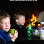 An image of Ty and Dylan having a mid afternoon snack near the fire in the Tramside Base Lodge at Jay Peak Ski Resort in Vermont