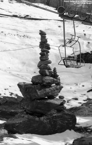A pile of balanced rocks sits at the base of the Vista Quad Chairlift at Bolton Valley Ski Resort in Vermont, with snow from a recent April storm in the background