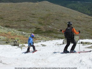 An image of Jay advising Dylan as he skies though a narrow area with rocks on the Mount Washington east snowfields - Memorial Day Weekend 2012