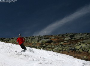 An image of Erica skiing the snowfields on Mount Washington in New Hampshire, with a stripe of cirrus clouds among blue sky in the background