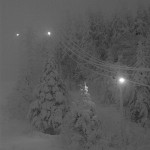 An image of snow covered trees and night skiing lights on the upper mountain in mid afternoon due to low clouds and December darkness at Bolton Valley Ski Resort in Vermont