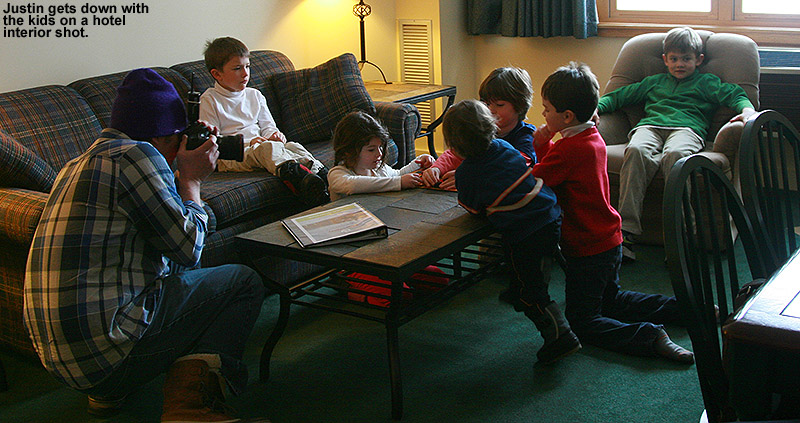 An image of a photographer working with children in a hotel room at Bolton Valley Ski Resort in Vermont as he takes lifestyle photos