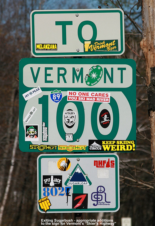 An image of a Route 100 highway sign in Vermont covered with a variety of ski stickers