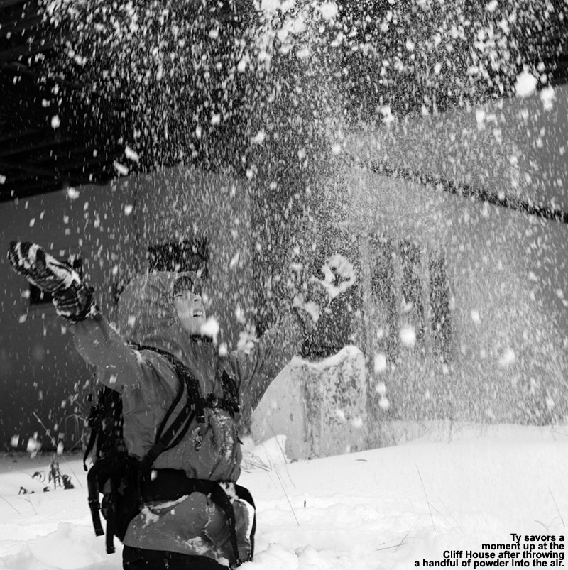 An image of Ty throwing a handful of October powder into the air at the Cliff House at Stowe Mountain Resort in Vermont