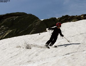 An image of Dylan skiing one of the snowfields on Mt. Washington in New Hampshire in June among some massive boulders