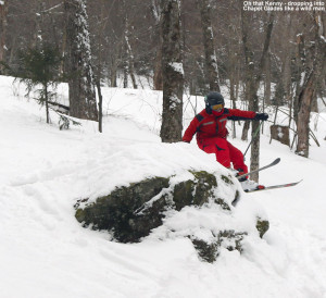 An image of Kenny jumping off a rock as he skis in the Chapel Glades at Stowe Mountain Resort in Vermont