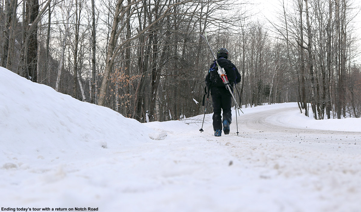 An image of Jay hiking with skis his pack on Bolton Notch Road in Vermont to return to his car