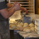An image showing the cooks at Fireside Flatbread pizza at Bolton Valley Ski Resort as they prepare balls of dough for the pizza crusts