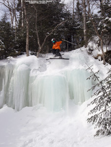 An image of Ty jumping off a large frozen waterfall on skis at Stowe Mountain Resort in Vermont
