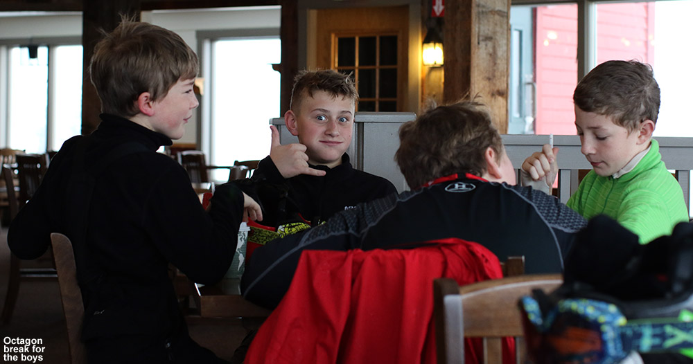 An image showing some boys in the BJAMS ski program having a snack at the Octagon atop Stowe Mountain Resort in Vermont