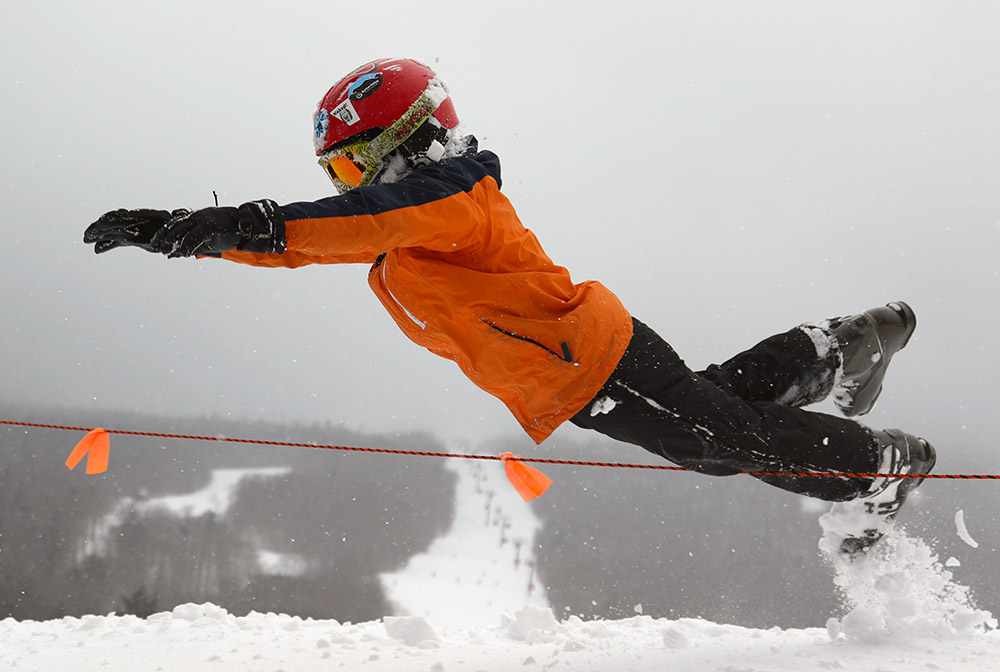 An image of Dylan jumping into powder at Stowe Mountain Resort