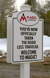 An image of a sign at Magic Mountain Ski Area in Vermont stating "You've now officially take the road less traveled - Welcome to Magic"