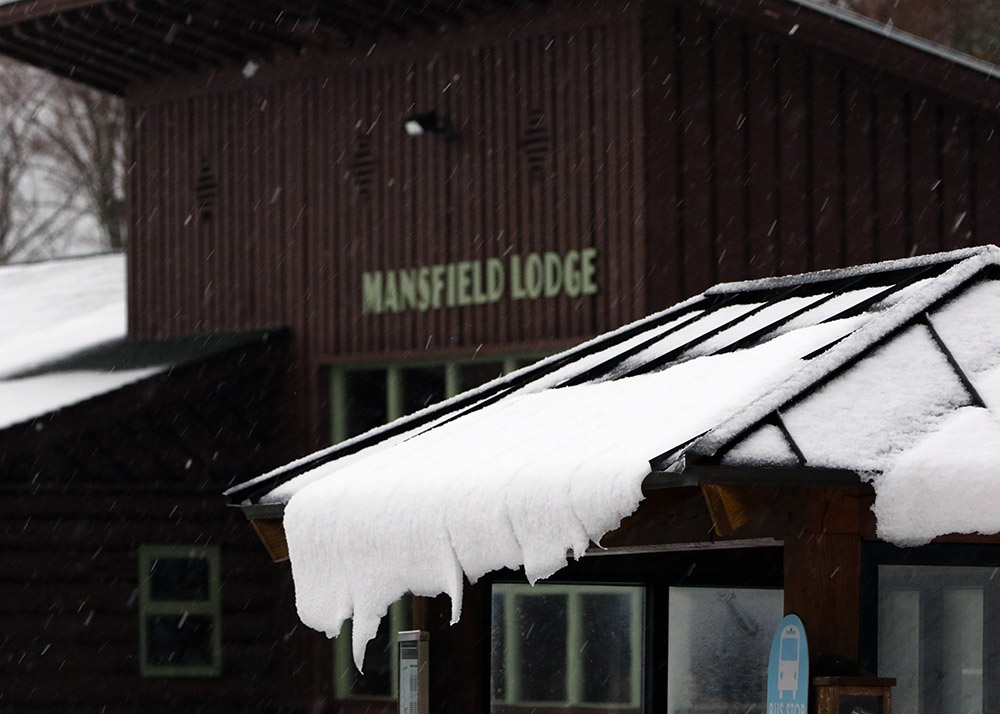 An image of snow sliding off a roof in front of the Mansfield Base Lodge at Stowe Mountain Resort in Vermont as an October nor'easter affects New England