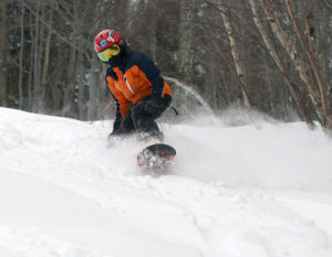 An image of Dylan snowboarding in powder on Upper Meadows at Stowe Mountain Resort in Vermont