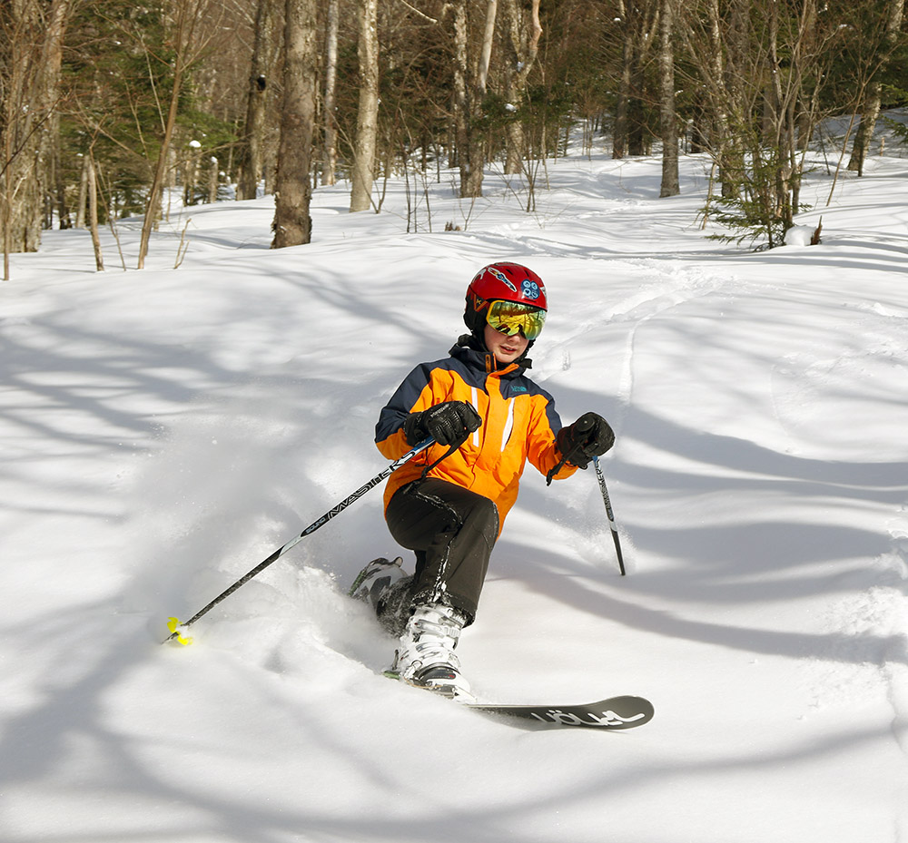 An image of Dylan Telemark skiing in powder at Bolton Valley Resort in Vermont.