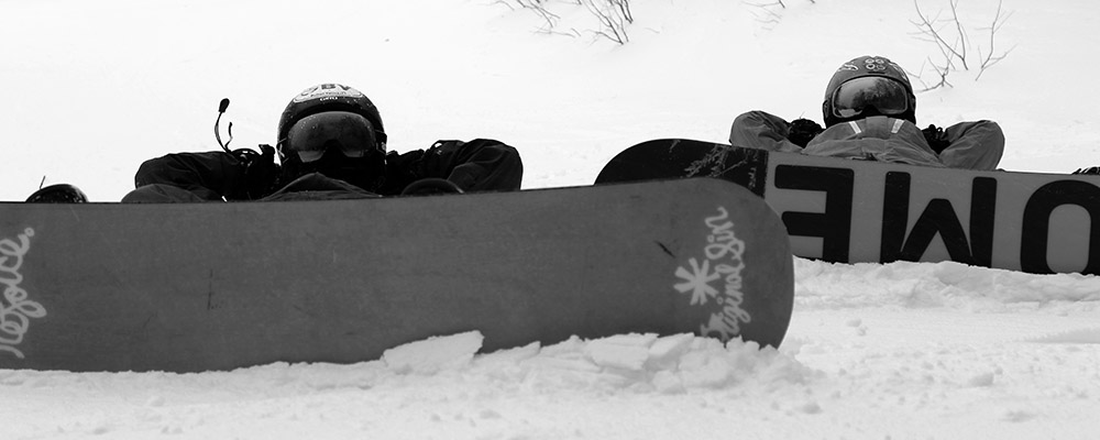 Ty and Dylan lying down on the snow with their snowboards on at Stowe Mountain Resort in Vermont