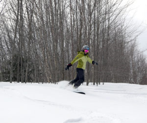 An image of Erica snowboarding in powder in the Toll House area at Stowe Mountain Resort in Vermont