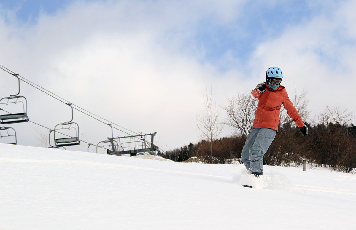 An image of Molly riding her snowboard in the Inspiration/Adventure Triple Chair area at Stowe Mountian Resort in Vermont after some back side snow from Winter Storm Ulmer