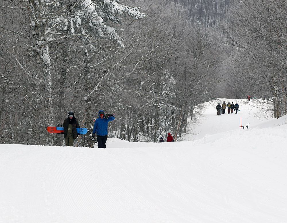 An image of skiers and snowboarders hiking up the Villager trail at Bolton Valley in Vermont