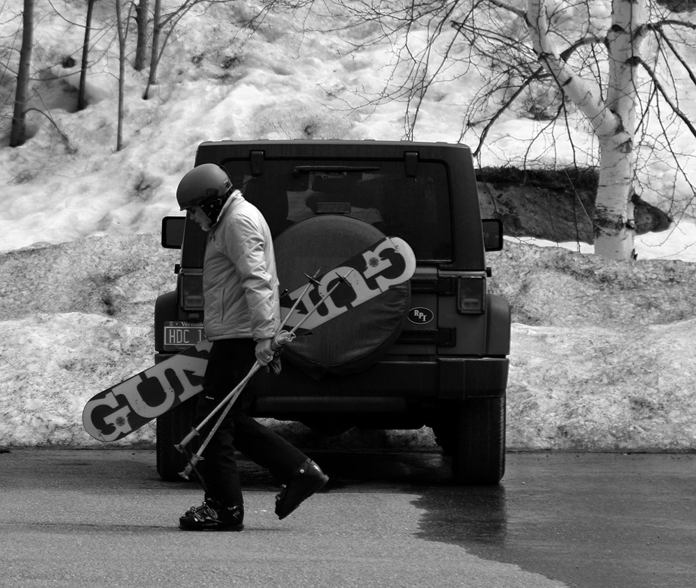 An image of a man with a monoski walking through the Timberline parking lot at Bolton Valley Resort in Vermont