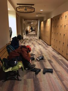 An image of Ty and Dylan getting their ski gear on in the locker area of the Spruce Camp base lodge at Stowe Mountain Resort in Vermont.